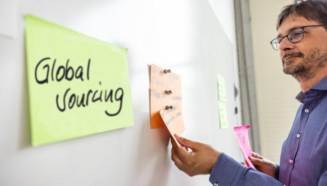 Mann am Whiteboard mit Post-IT Global Sourcing